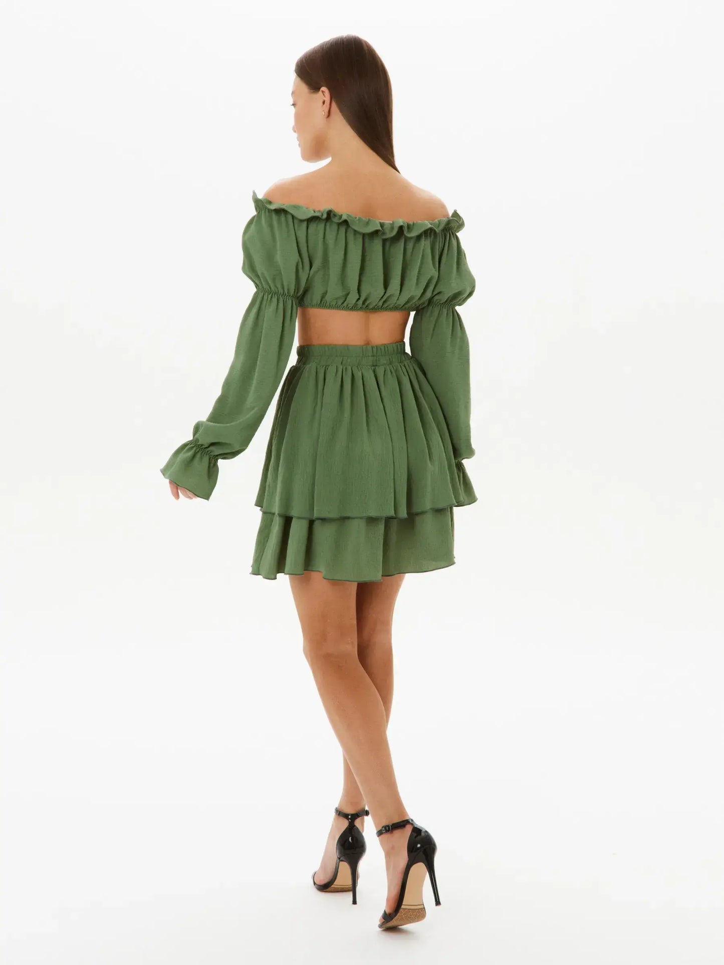 Back view of a woman in a tiered ruffle set featuring an off-shoulder crop top and mini skirt in elegant khaki.