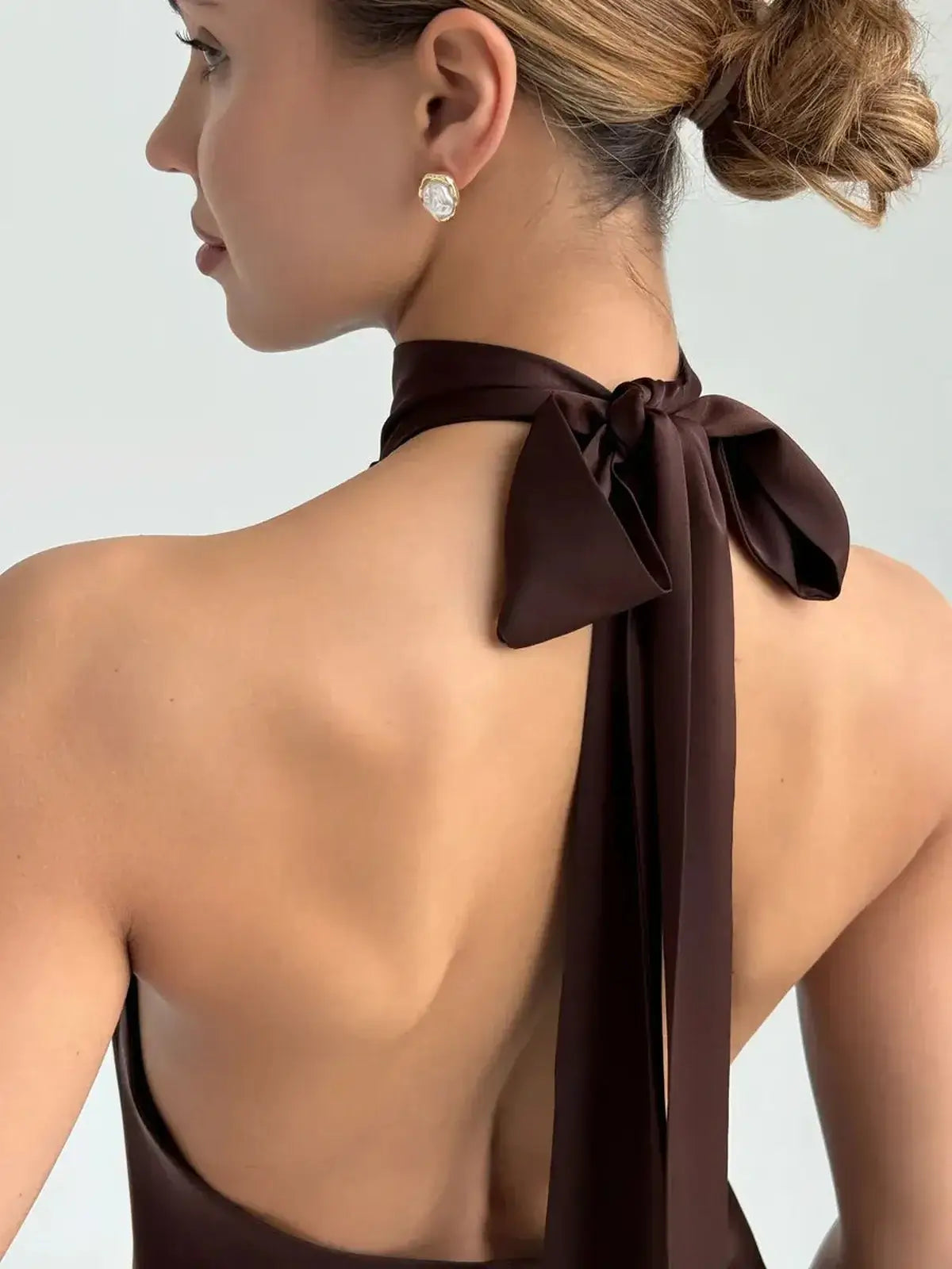 Model showcasing the elegant open back and sculptural bow tie of the Mocha Silk Mini dress.