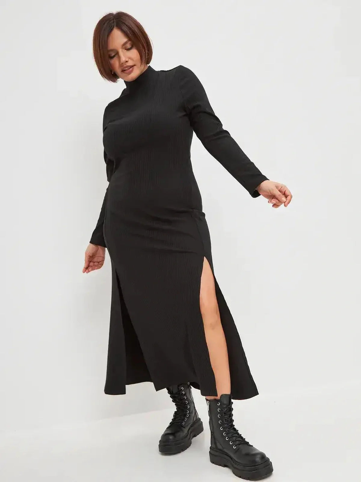 Black midi dress with ribbed texture and side slit, styled with combat boots for a chic, modern look.