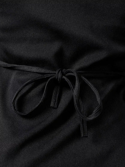 Close-up of lace-up detail on a black ribbed mini dress showcasing elegance and style.