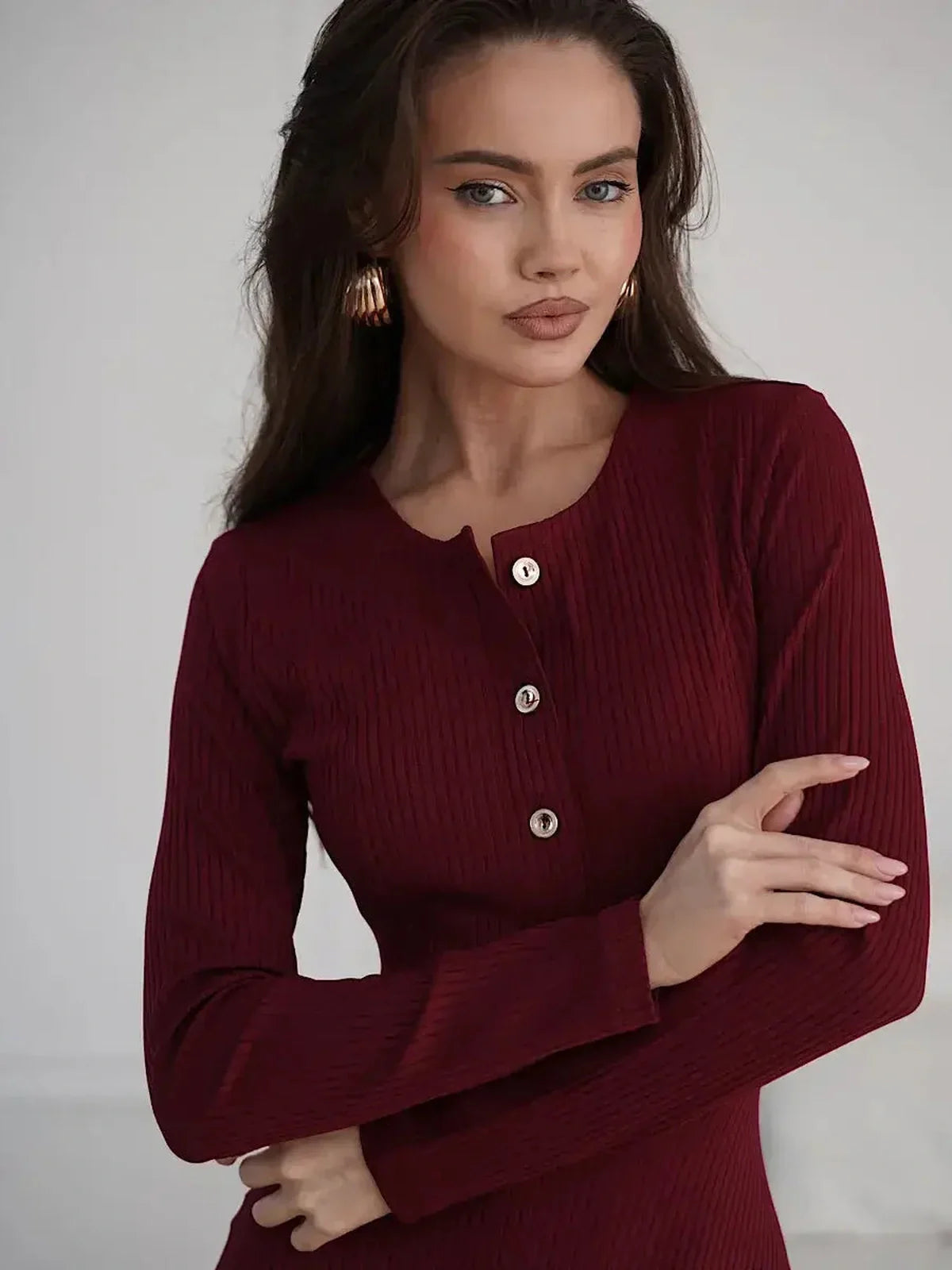 Model wearing the Crimson Grace Midi Dress with gold button detail in rich burgundy, showcasing a ribbed texture.