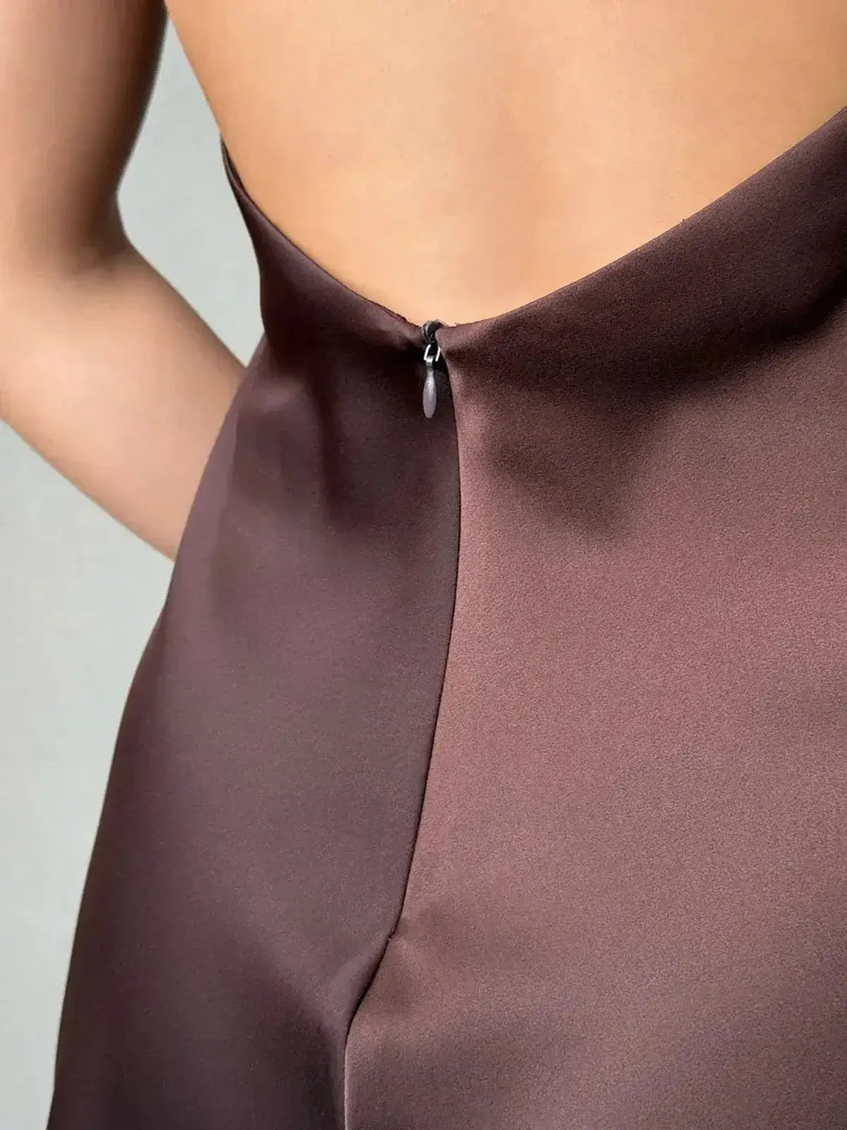 Close-up of the Mocha Silk Mini dress showcasing the elegant open back and sculptural bow tie detail.