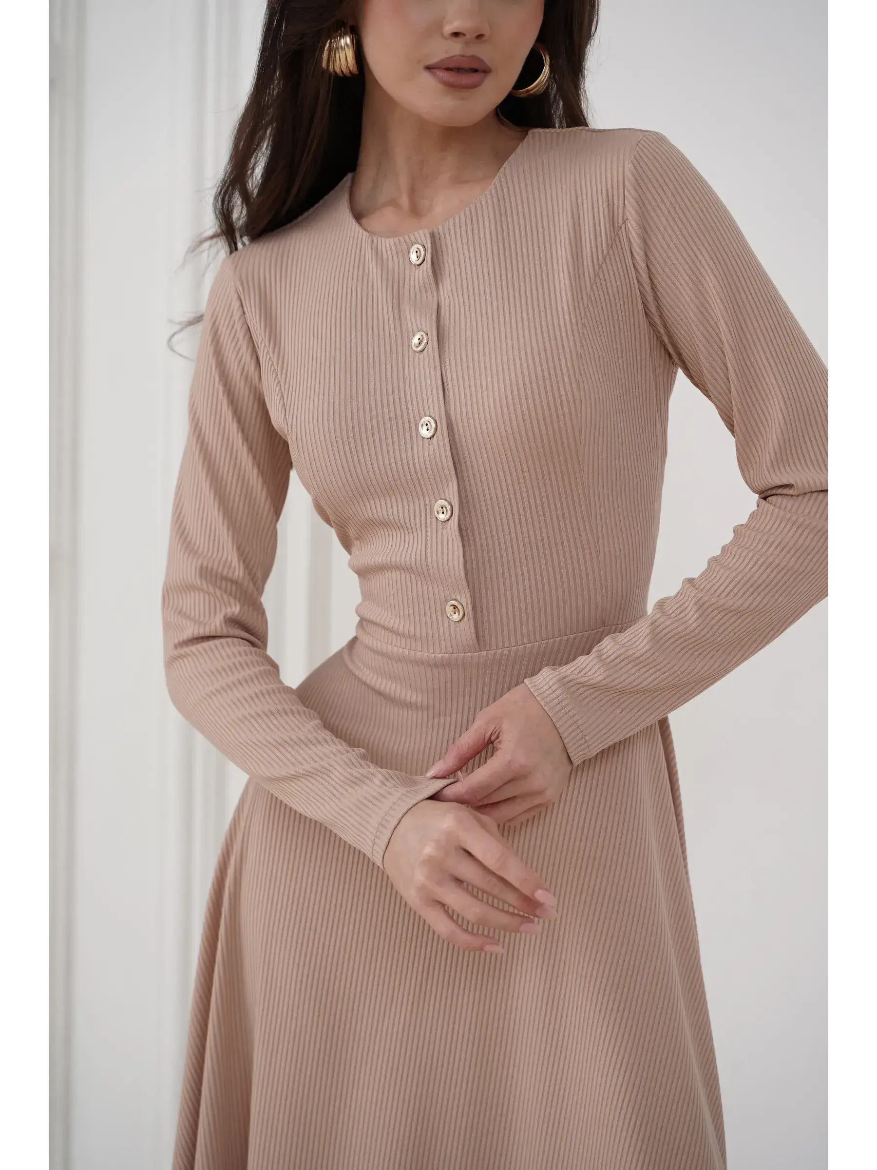 Elegant sculpted midi dress in smooth beige ribbed knit with gold-tone buttons, perfect for formal and casual occasions.