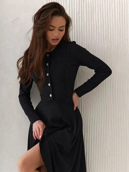 Model showcasing the Serene Grace Midi Dress in black ribbed fabric, featuring decorative buttons and a flared skirt.