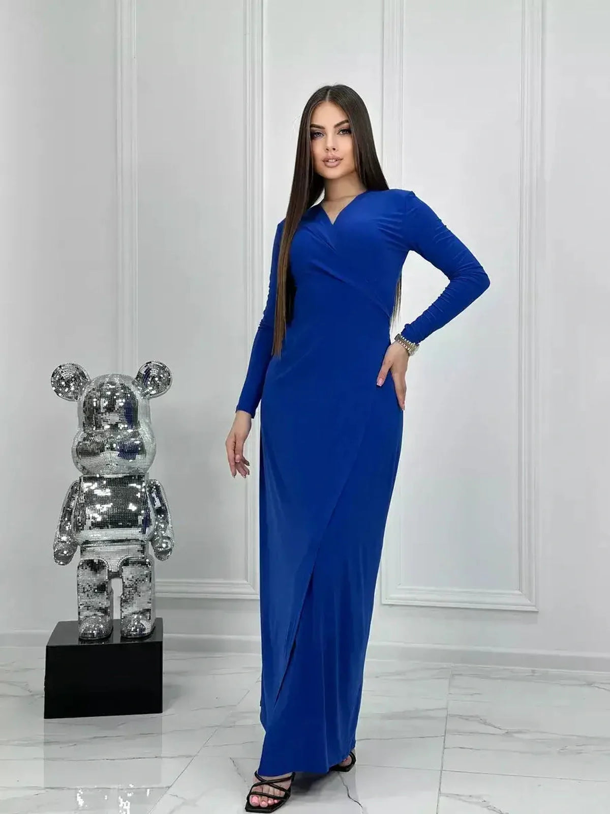 Model wearing a royal blue Sculptura Maxi Dress with long sleeves and a side slit, showcasing modern elegance.