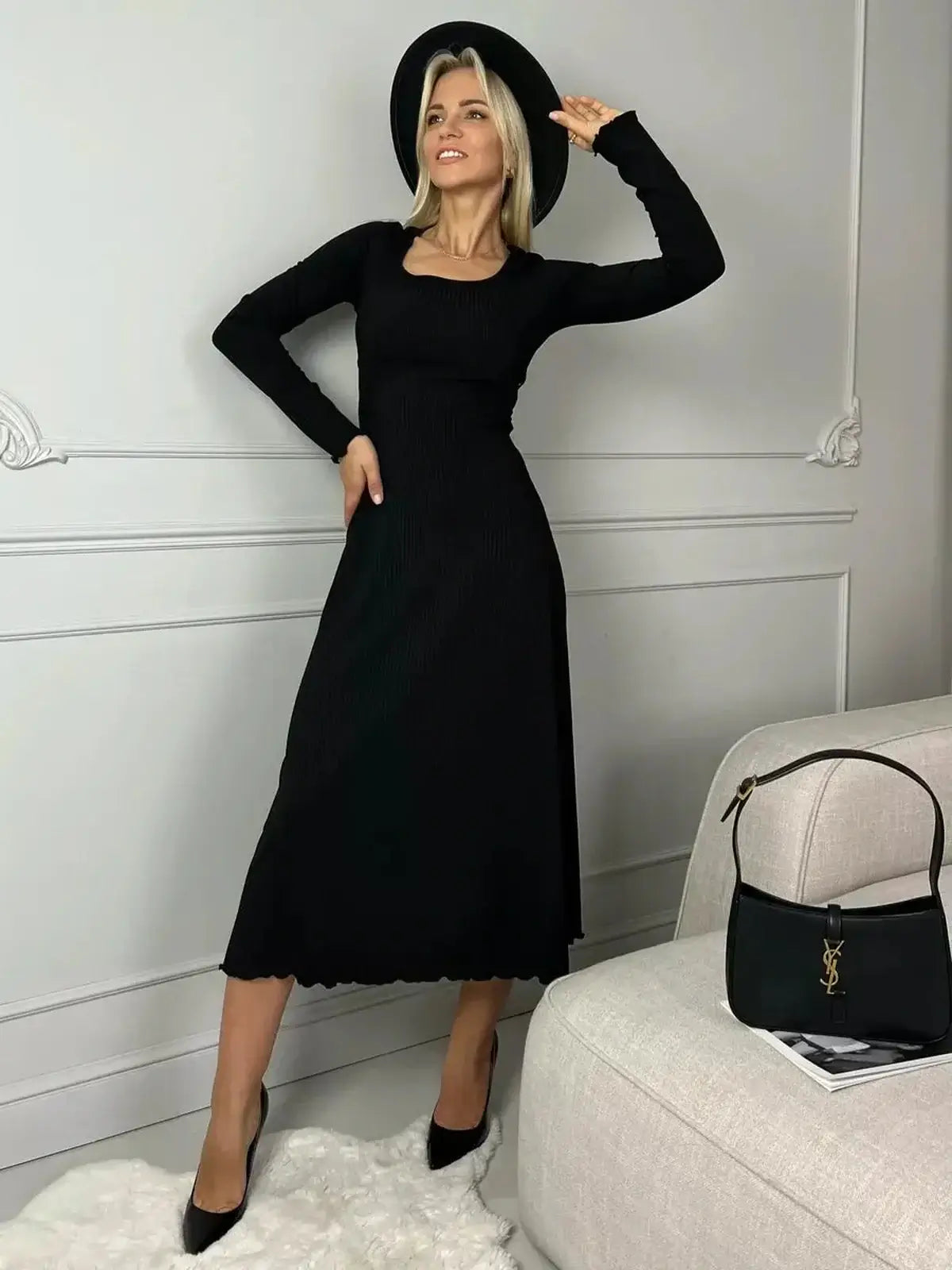 Model showcasing a Sculpted Grace Midi Dress, a black ribbed knit dress with long sleeves and a flared silhouette.