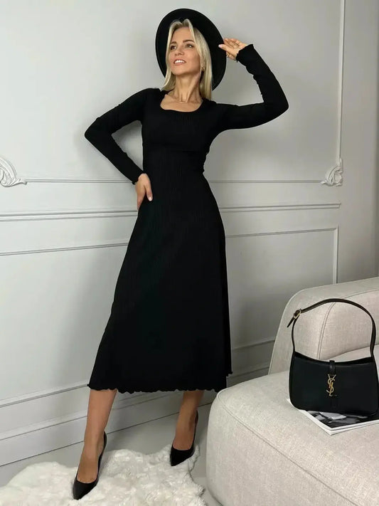 Model showcasing a Sculpted Grace Midi Dress, a black ribbed knit dress with long sleeves and a flared silhouette.