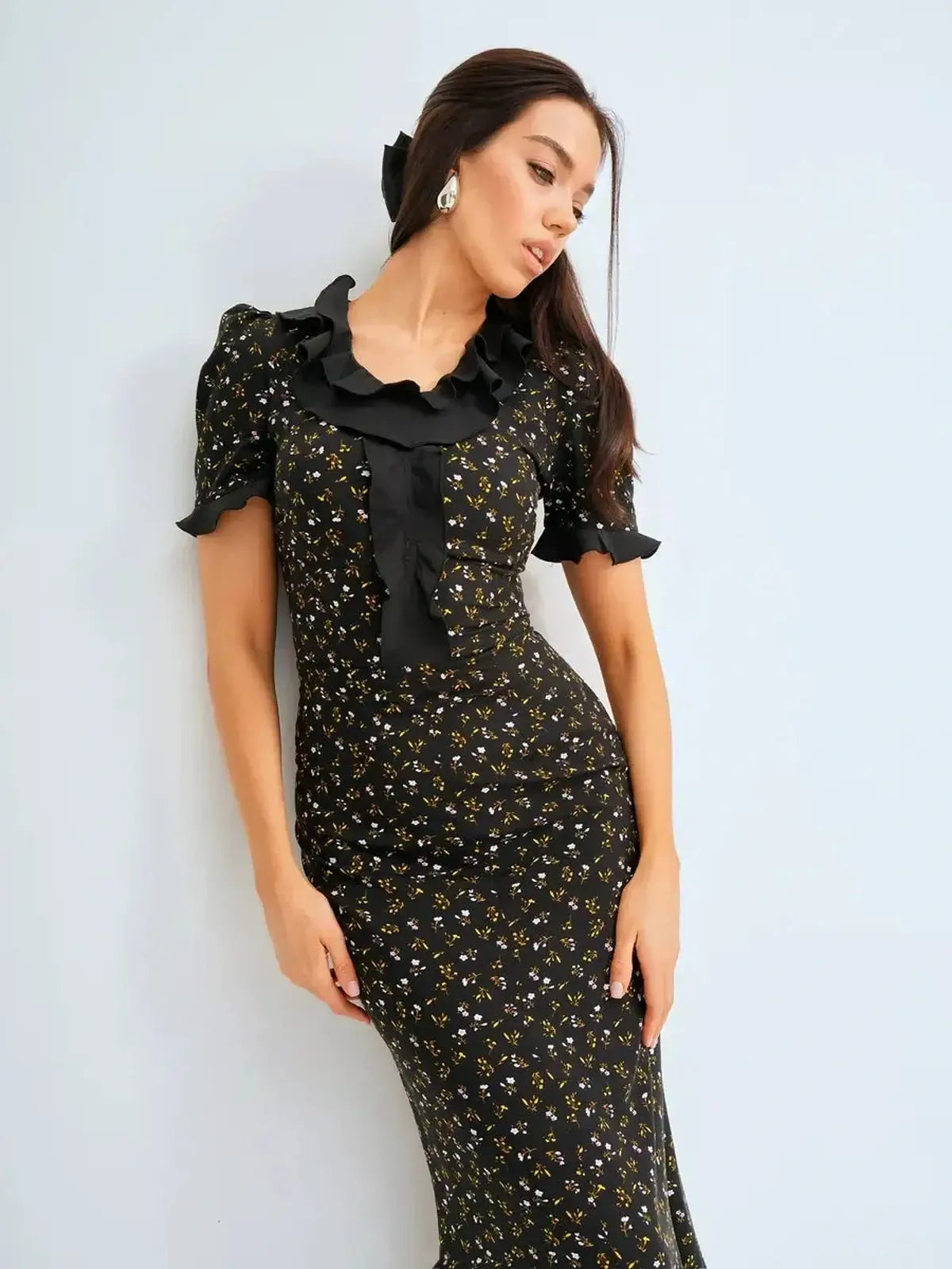 Elegantly posed model in floral printed black midi dress featuring ruffles, perfect for summer weddings and formal occasions.
