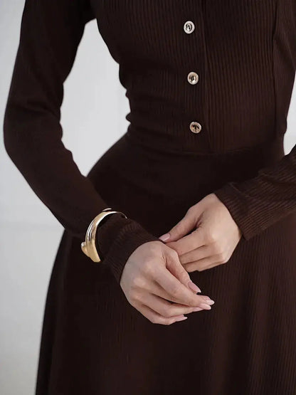 Close-up of a woman in a brown midi dress featuring button detailing and a stylish cuff, showcasing elegant fashion for various occasions.