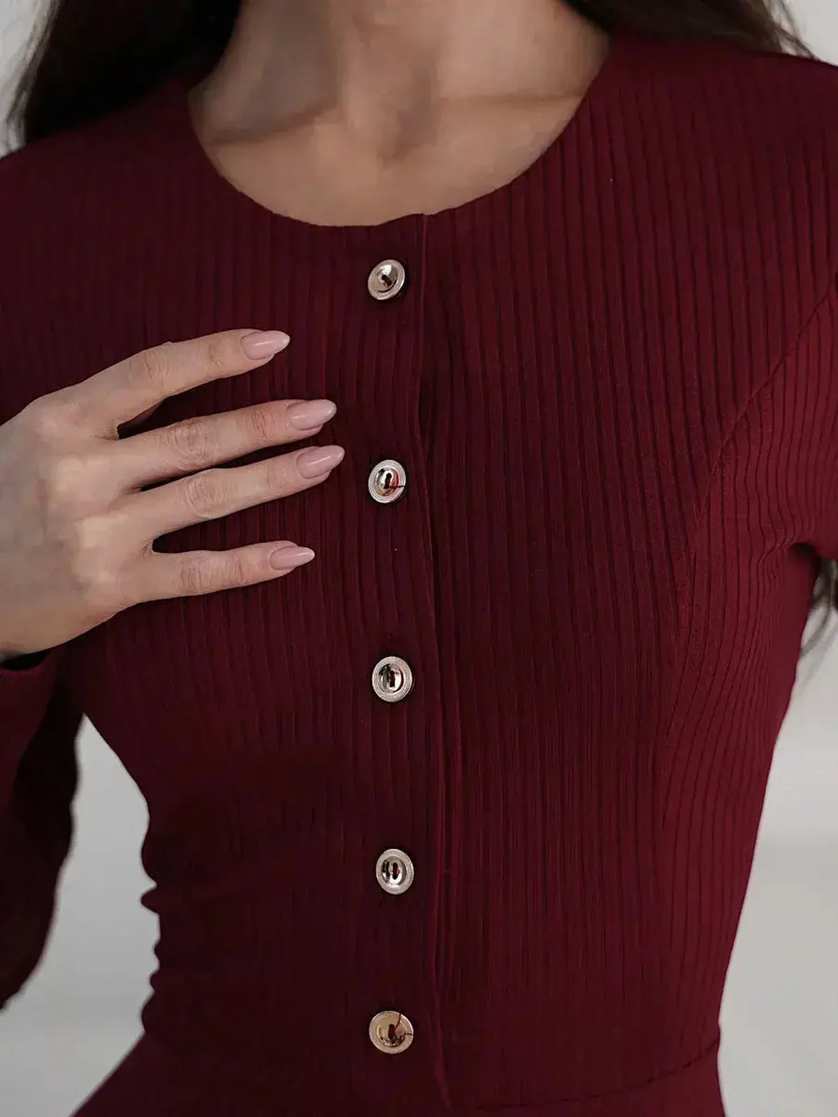 Close-up of a burgundy ribbed midi dress featuring gold-tone buttons, showcasing its elegant texture.