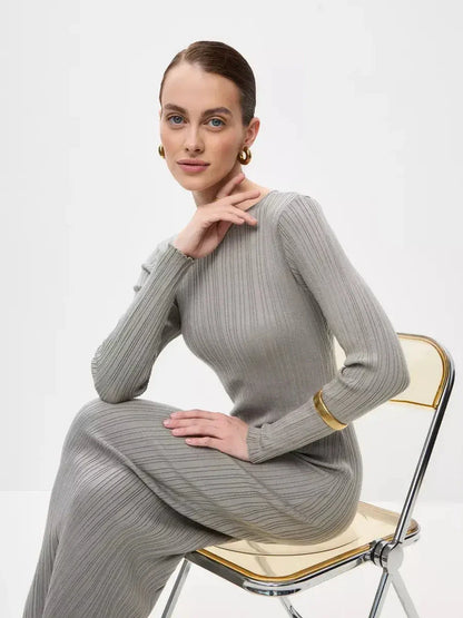 Stylish woman in a ribbed gray Sculpted Grace Maxi Dress seated on a chair, showcasing elegance and comfort.