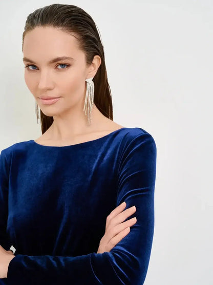 Model wearing a deep navy velvet dress with a boat neckline, showcasing modern elegance and stylish earrings.