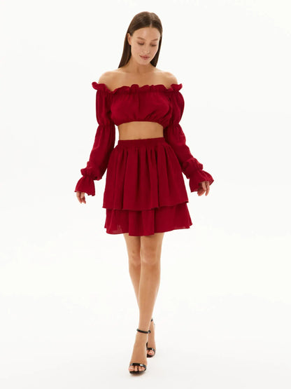 Ruffle summer set in burgundy featuring an off-shoulder crop top and tiered mini skirt, perfect for warm-weather occasions.