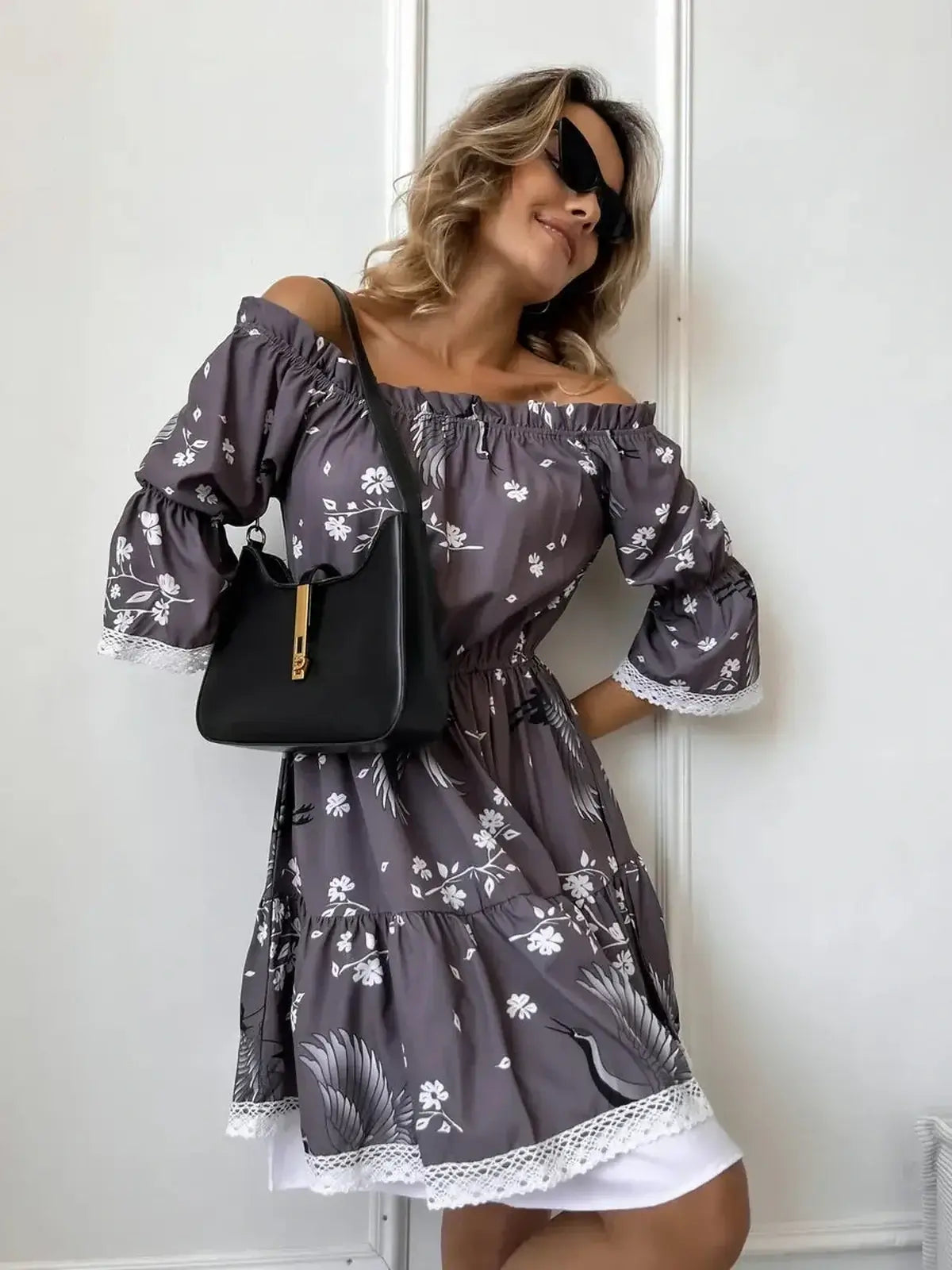 Woman in a grey-brown off-shoulder mini dress with ruffled sleeves, perfect for summer occasions and weddings.