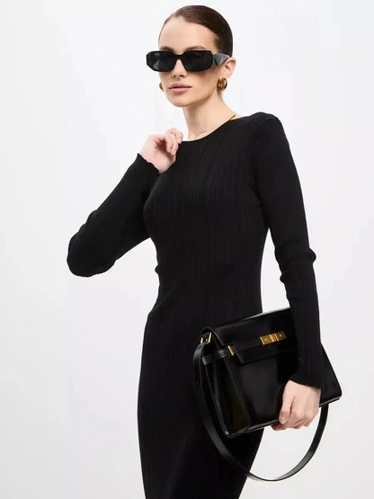Model wearing a sleek black Sculpted Rib Maxi Dress with sunglasses and a stylish handbag, showcasing modern elegance.