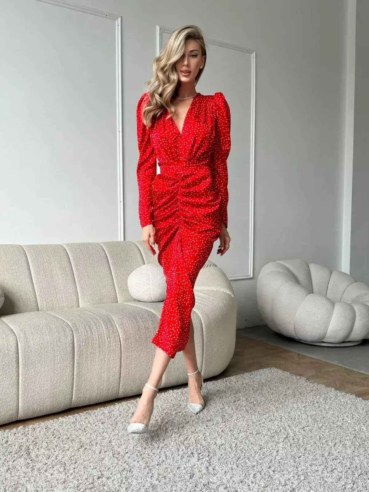 Elegant woman modeling the Starlight Midi Dress in radiant red with polka dots, showcasing ruched design and V-neckline.
