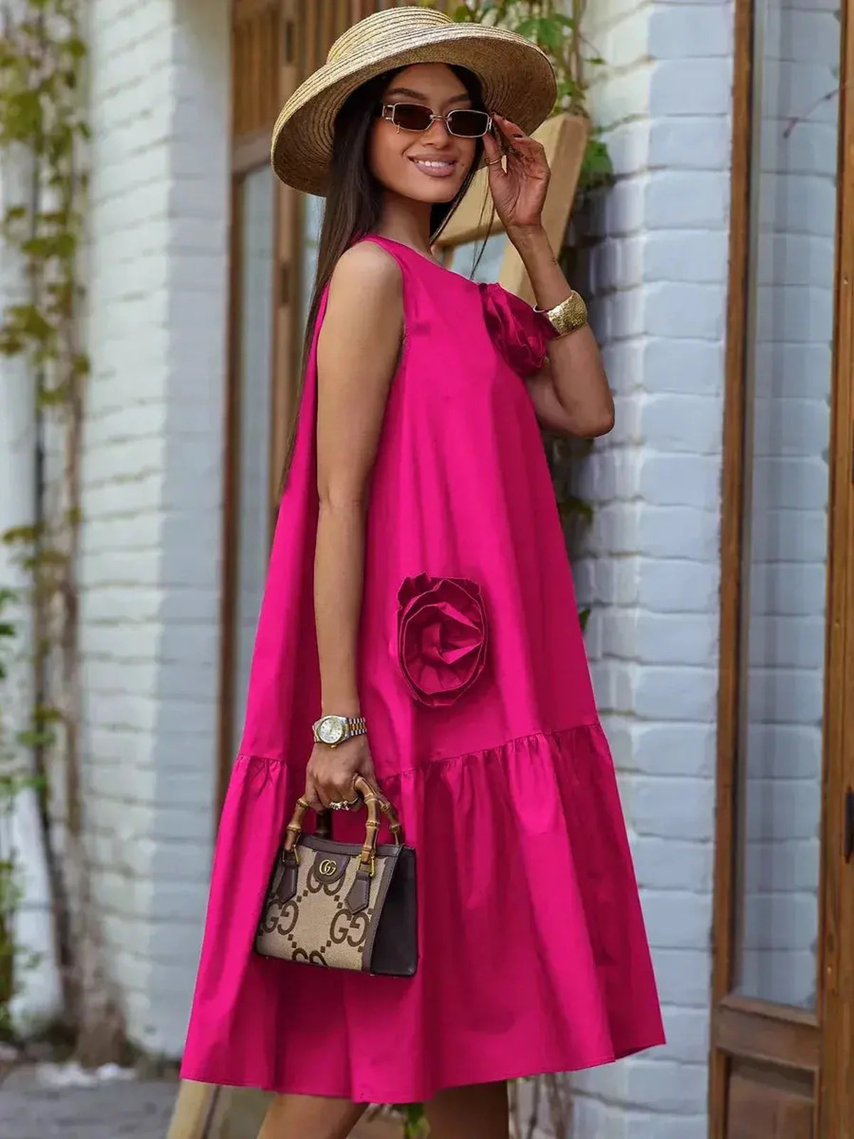 Woman in a bold fuchsia midi dress with oversized floral accents, perfect for summer outings and festive occasions.