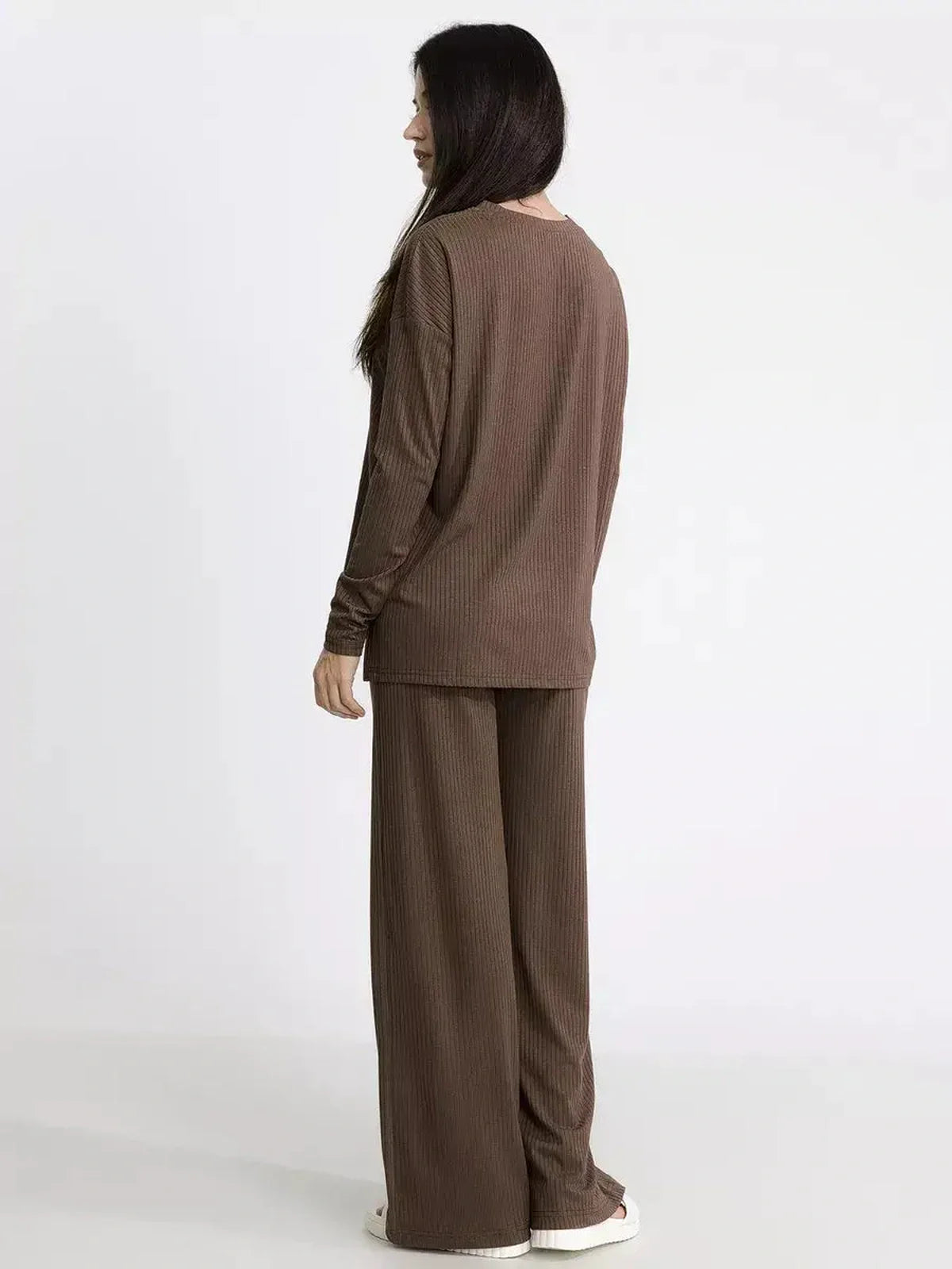 Back view of a woman in a soft brown ribbed knit lounge set, highlighting oversized comfort and minimalist design.