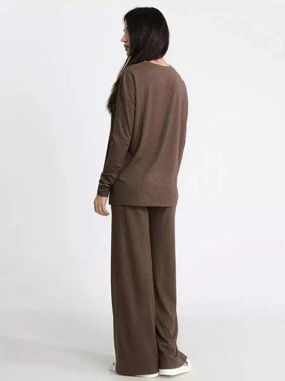 Back view of a woman in a soft brown ribbed knit lounge set, highlighting oversized comfort and minimalist design.