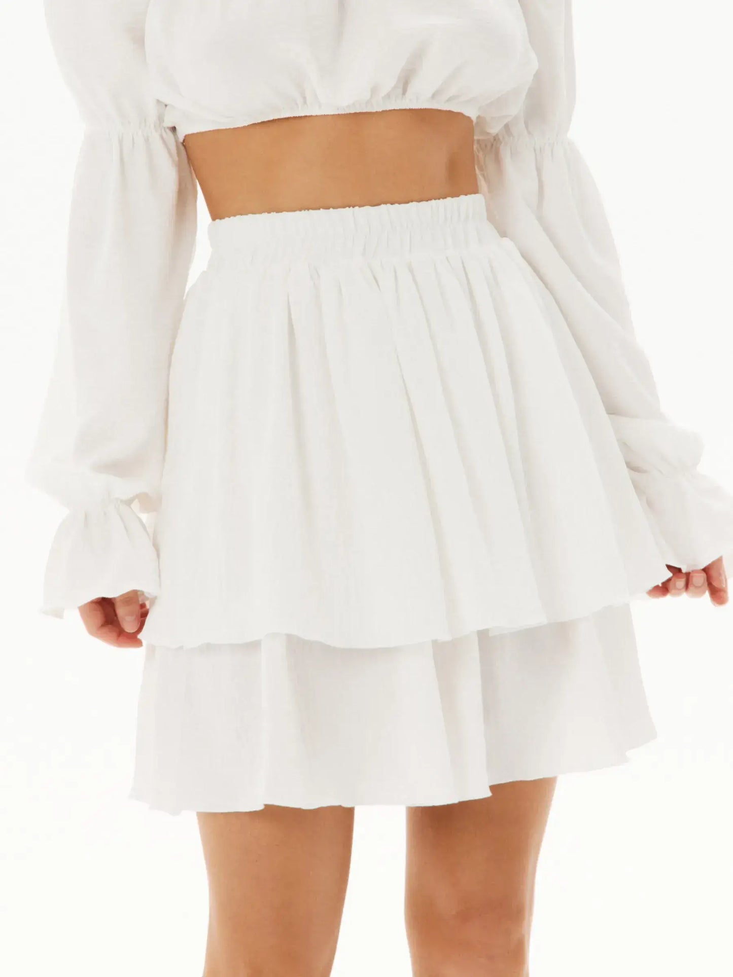 White ruffle mini skirt featuring a tiered design, perfect for summer occasions and stylish outfit pairings.