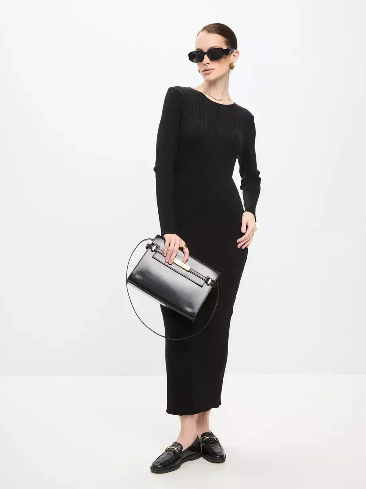 Chic model showcasing a Sculpted Rib Maxi Dress in black, accessorized with sunglasses and a stylish handbag.