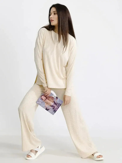 Trendy woman in beige oversized ribbed lounge set, styled with a magazine and sandals, ideal for casual comfort.