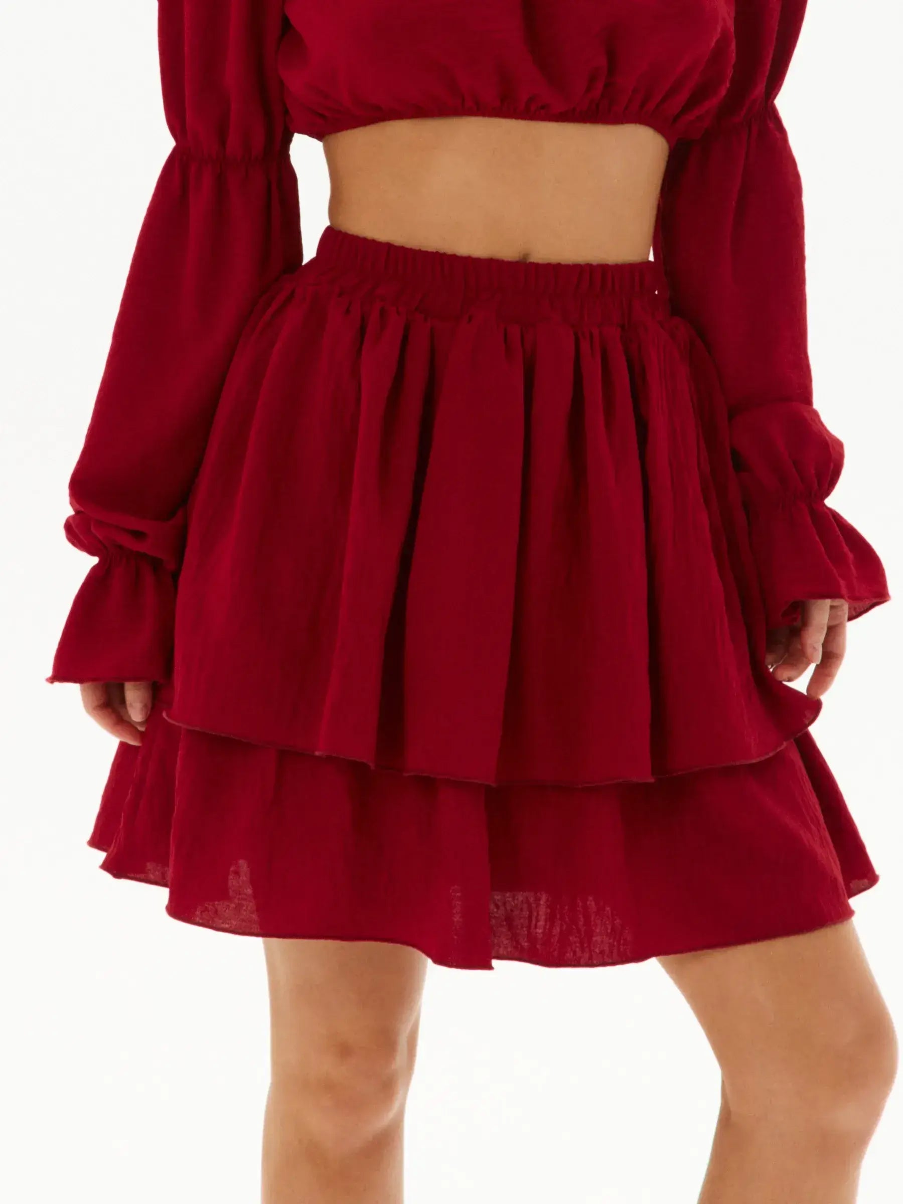 Ruffle summer set featuring a burgundy off-shoulder crop top and tiered mini skirt, perfect for warm-weather occasions.