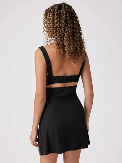 Back view of a woman in a sleek black mini dress with wide straps, showcasing a flattering silhouette.