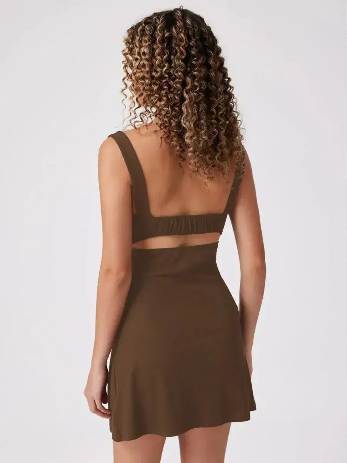 Back view of a sculpted cutout mini dress in olive, featuring wide straps and a flared hem for a chic summer look.