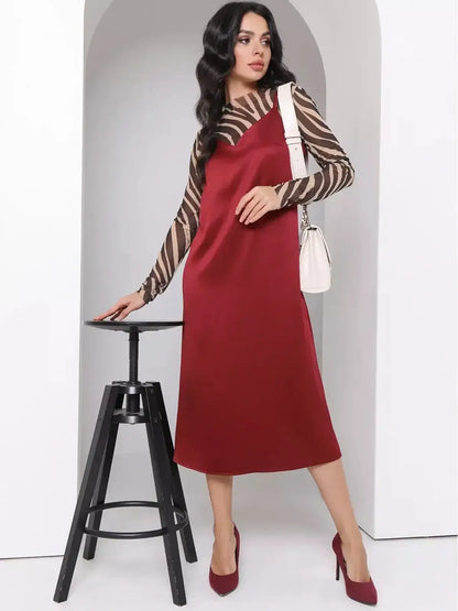 Model wearing a burgundy Satin Charm Midi Dress with adjustable straps, styled with a striped top and heels.