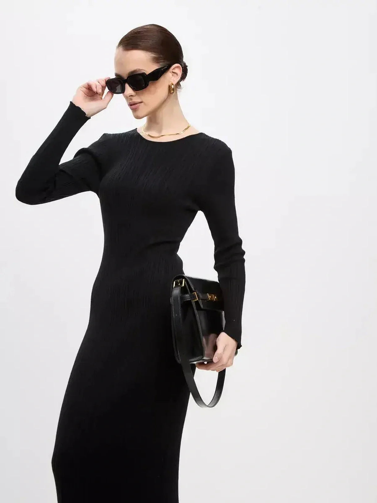 Model wearing a sleek black Sculpted Rib Maxi Dress, styled with sunglasses and a handbag for a chic look.