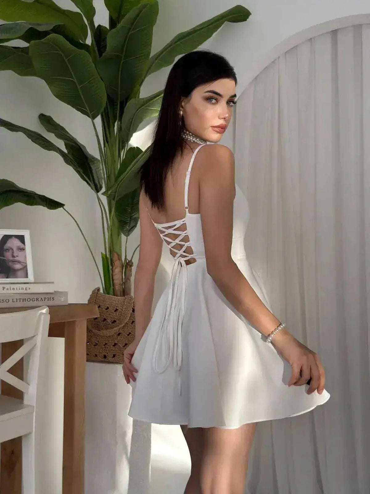 Model showcasing the Laceback Muse white dress with a lace-up corset back, perfect for summer events and wedding guest attire.