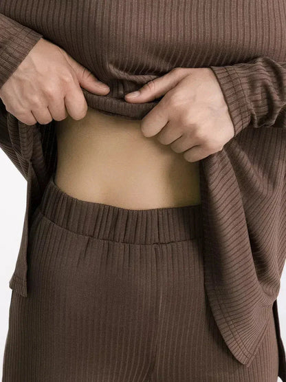 Close-up of a model adjusting the waistband of a soft, ribbed brown lounge set for relaxed comfort.