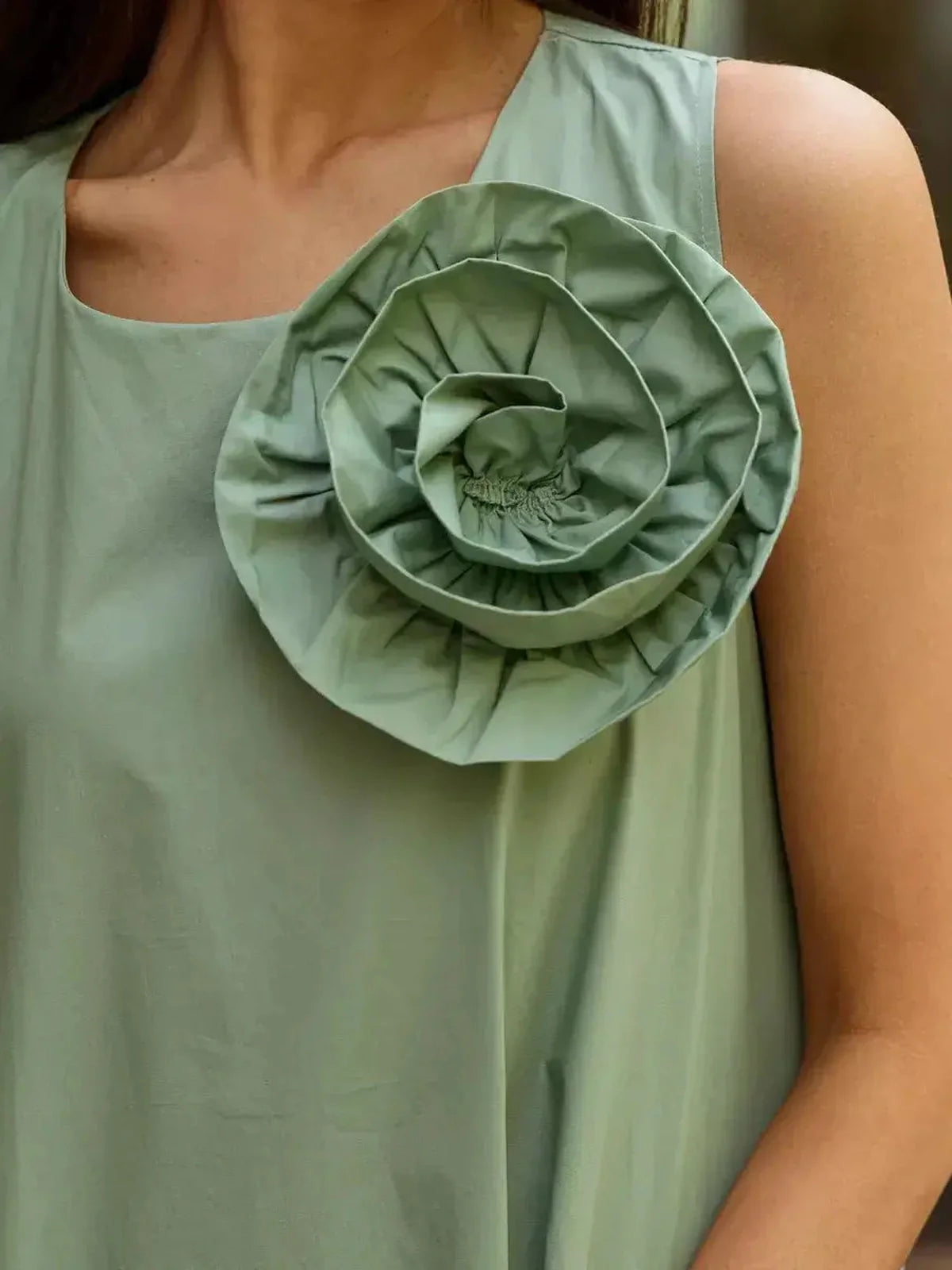 Close-up of the Petal Bloom Midi Dress featuring a stunning green rosette embellishment on a sleeveless design.