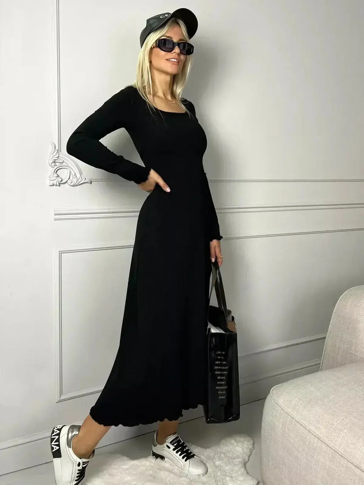 Model wearing a black Sculpted Grace Midi Dress with flared silhouette and casual sneakers.