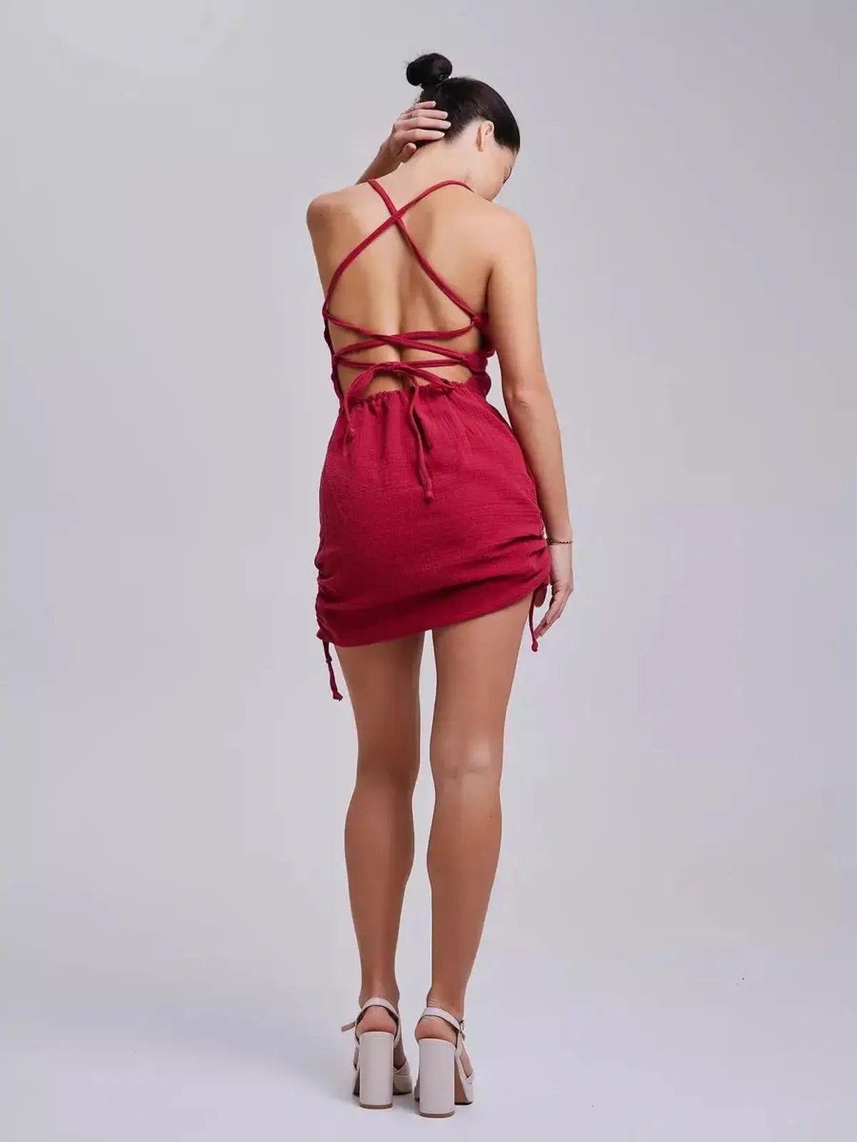 Back view of a woman in a red mini dress with lace-up detailing, ideal for summer or wedding guest attire.