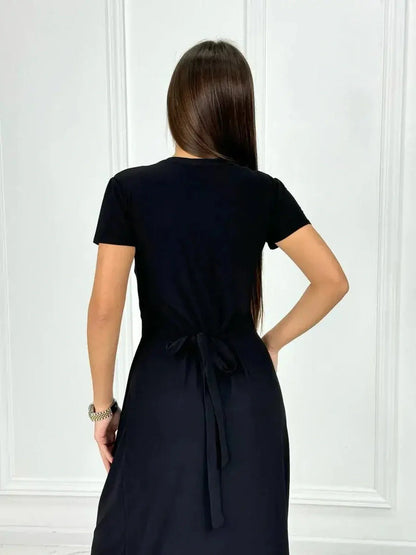 Back view of a woman wearing an elegant black maxi dress with a tie detail, perfect for casual summer styling.