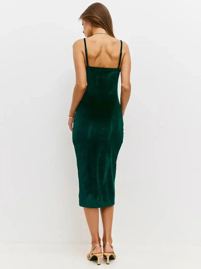 Back view of a woman wearing the Midi Dress Emerald Dusk in rich emerald velvet, showcasing its sleek silhouette and fine straps.