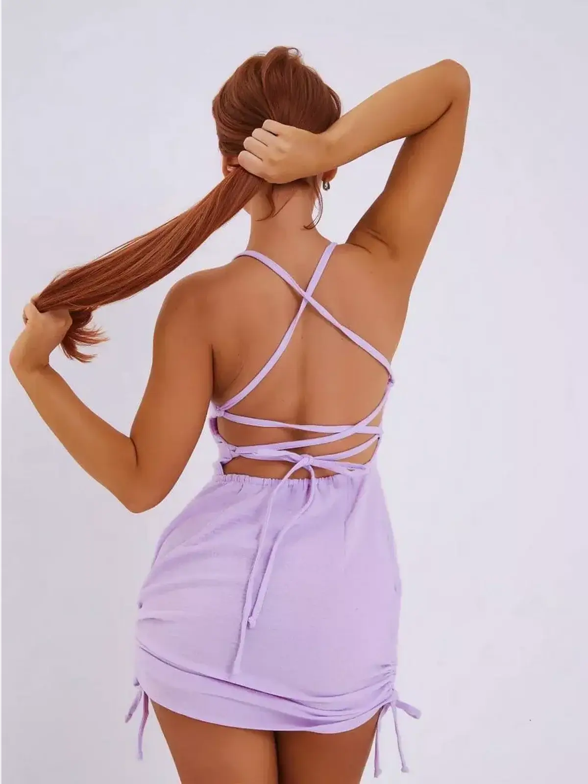 Back view of a woman in a lilac mini dress with criss-cross straps, ideal for summer dresses and casual outings.