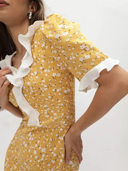 Detail of the Golden Muse Midi Dress featuring a yellow floral pattern and elegant ruffled sleeves with a white collar.