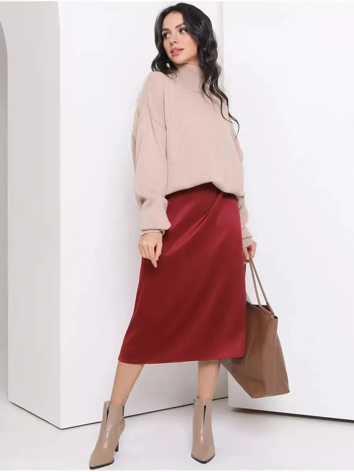 Model showcasing a satin midi dress in burgundy paired with a cozy sweater and beige ankle boots.
