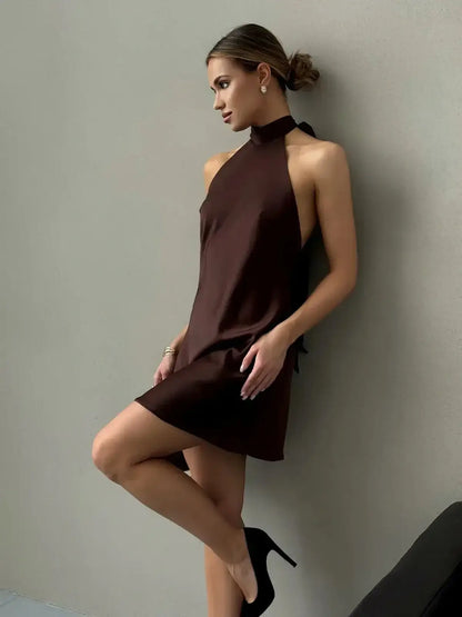 Model showcasing a chic Mocha Silk Mini dress with a halter neckline and open back, ideal for wedding guest or cocktail events.