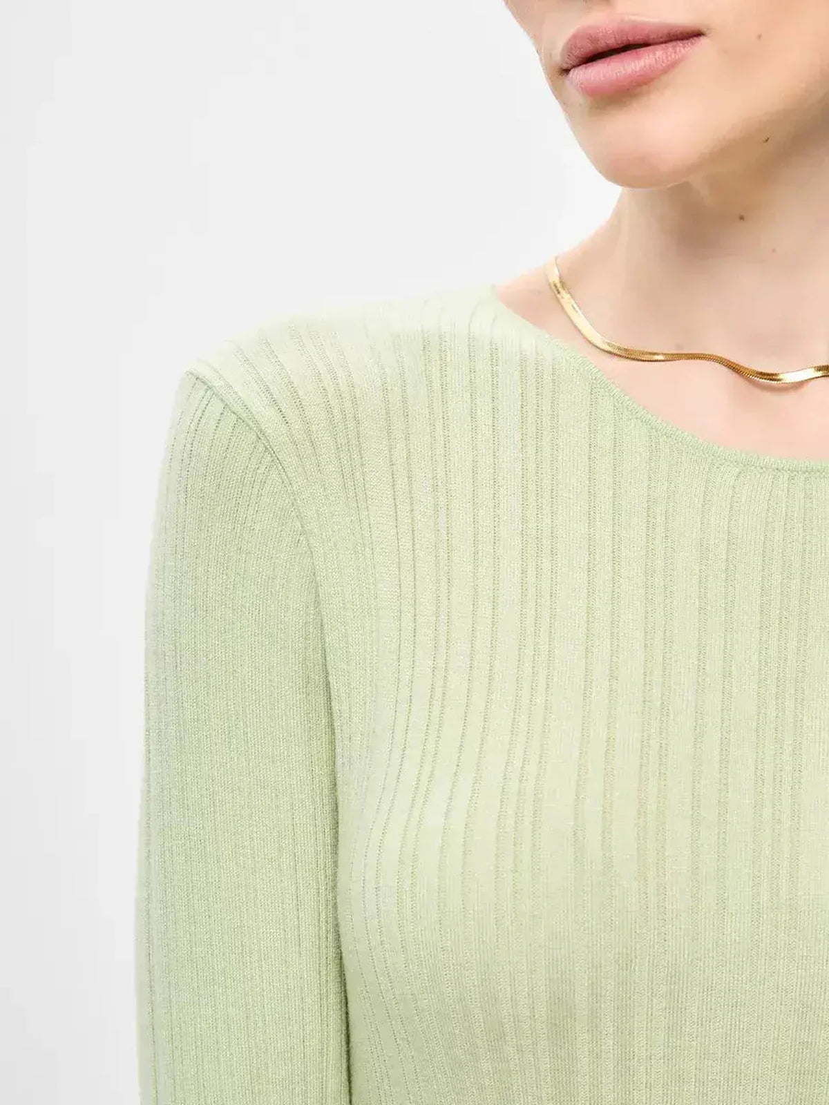 Close-up of a woman wearing the Celery Luxe Maxi Dress in light green ribbed knit, featuring a stylish necklace.