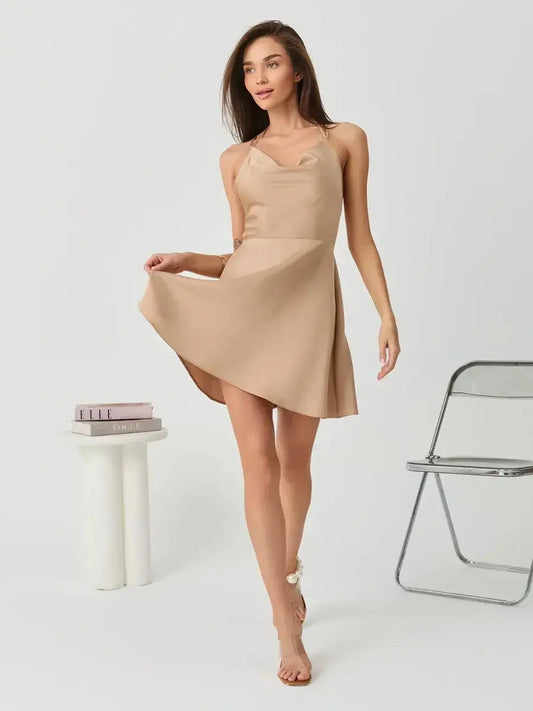 Model showcasing the Satin Whisper mini dress in beige, featuring spaghetti straps and a flared A-line silhouette, ideal for summer.
