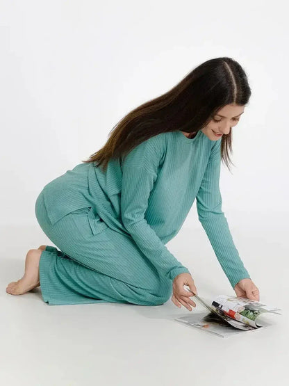 Woman in mint lounge set reading a magazine, showcasing soft ribbed comfort and relaxed fit for stylish loungewear.