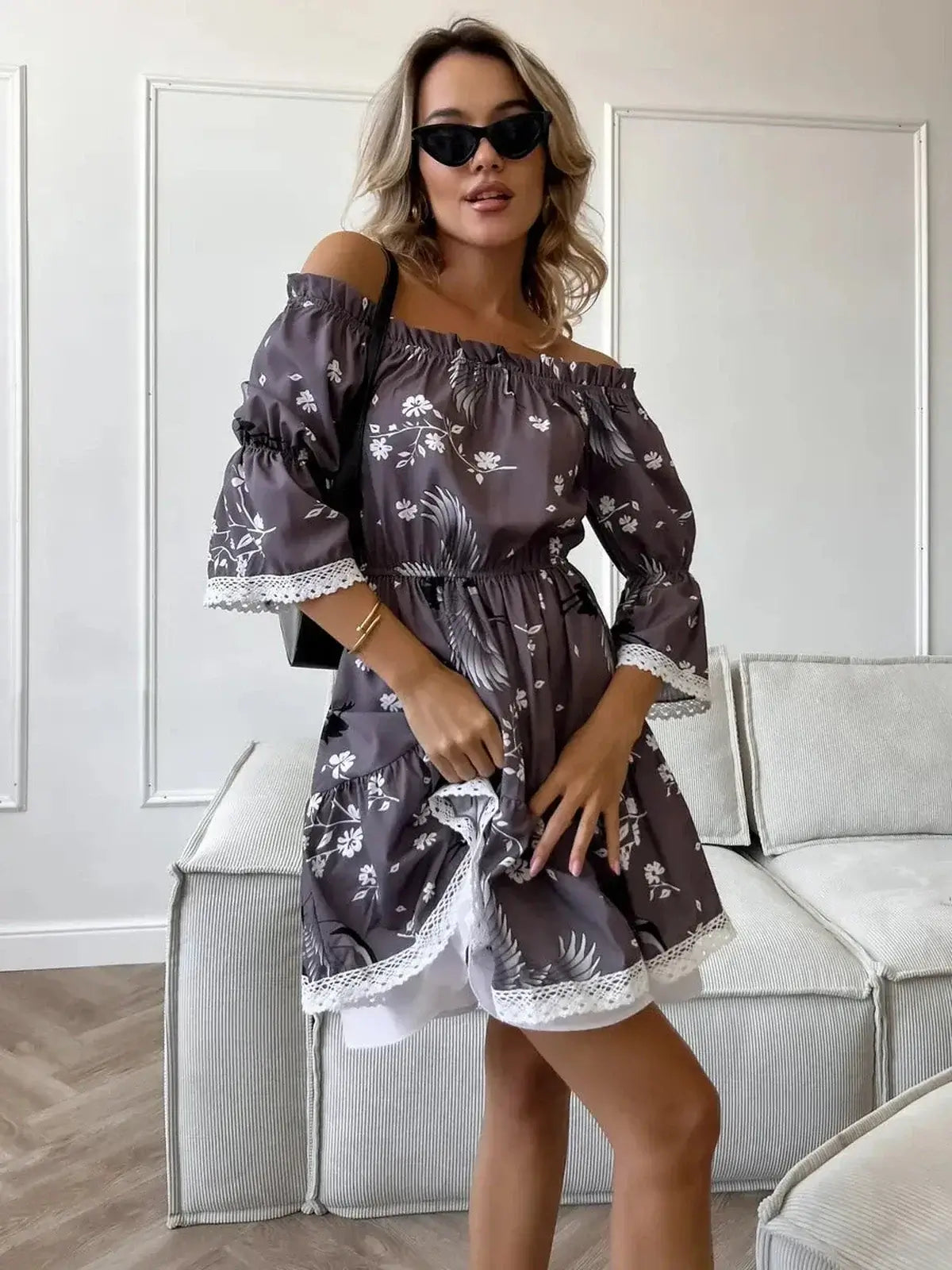 Sakura Flight mini dress featuring off-shoulder neckline, ruffled sleeves, and floral patterns in grey-brown fabric.