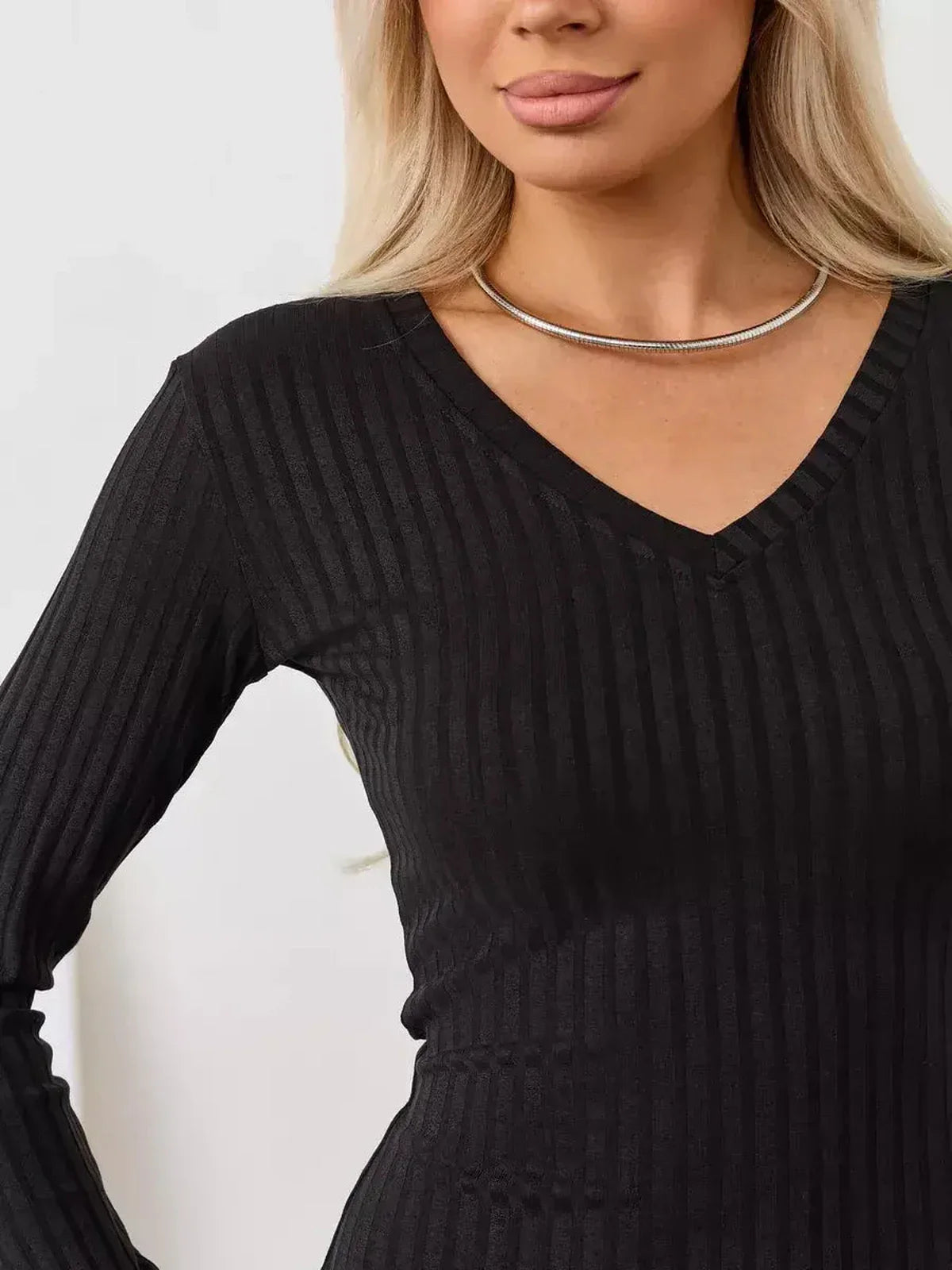 Closeup of a woman in a black ribbed V-neck midi dress, showcasing a sleek, minimalist design perfect for formal or casual occasions.