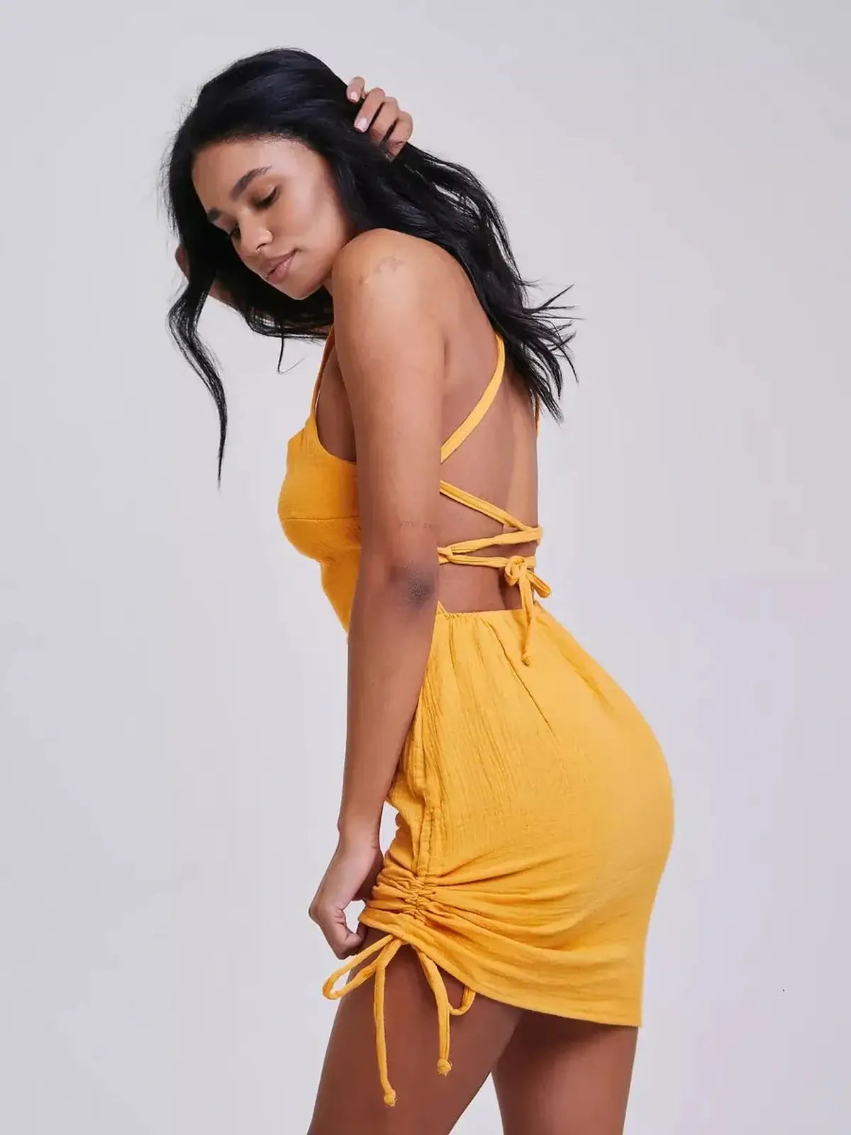 Model showcasing the Citrus Rush yellow mini dress with crisscross straps, perfect for summer and special occasions.