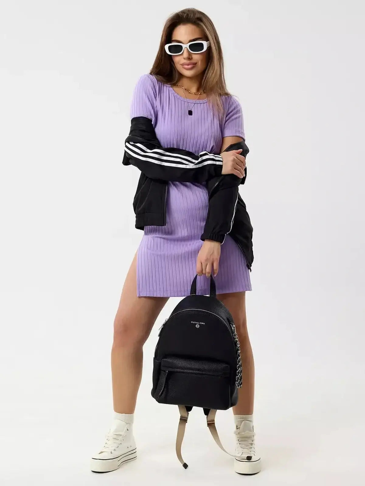 Model wearing a Lilac Ripple mini dress with short sleeves and side slits, styled with a black jacket and backpack.