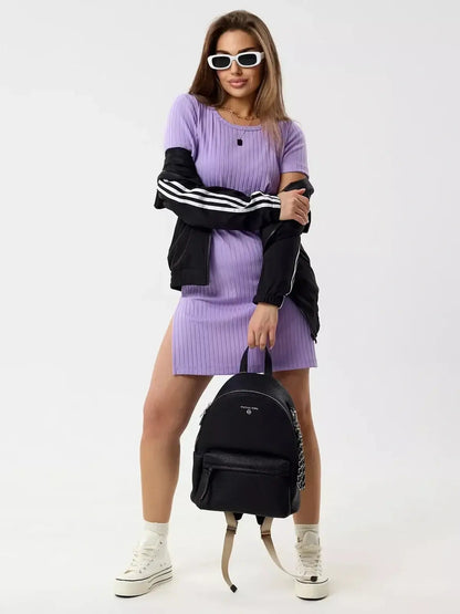 Model wearing a Lilac Ripple mini dress with short sleeves and side slits, styled with a black jacket and backpack.